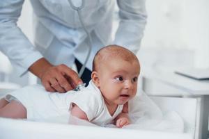 Junge Kinderärztin ist tagsüber mit kleinem Baby in der Klinik foto