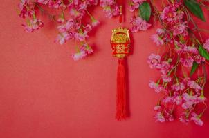 hängender anhänger für chinesische neujahrsverzierung bedeutung des wortes ist reich mit chinesischen blütenblumen auf rotem hintergrund. foto