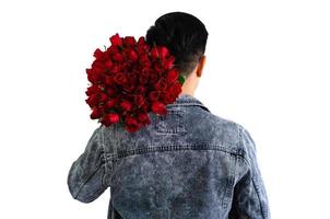 asiatischer Mann in Jeansjacke mit einem Strauß roter Rosen isoliert auf weißem Hintergrund für Jubiläums- oder Valentinstag-Konzept. foto