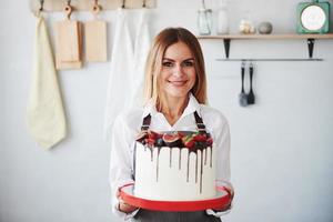 Frau steht drinnen in der Küche mit hausgemachtem Kuchen foto