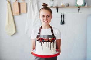 Frau steht drinnen in der Küche mit hausgemachtem Kuchen foto