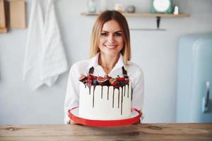 Frau steht drinnen in der Küche mit hausgemachtem Kuchen foto