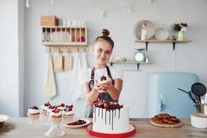 Frau steht drinnen in der Küche mit hausgemachtem Kuchen foto