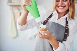 Frau steht drinnen in der Küche mit hausgemachtem Kuchen foto