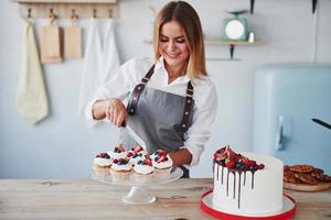 Frau steht drinnen in der Küche mit hausgemachtem Kuchen foto