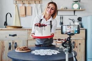 Frau macht leckere Süßigkeiten und Kuchen. Aufnahmevorgang per Smartphone auf Stativ foto