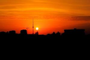 Kiewer Fernsehturm. dunkle Silhouette von schwarzen Gebäuden und Fernsehturm mit farbenfroher, leuchtend orangefarbener Sonnenuntergangssonne. Ukraine, Kiew foto