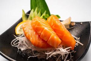 sashimi, lachs, japanische essstäbchen und wasabi auf dem weißen tisch foto