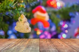 leere hölzerne tischplatte mit unscharfem weihnachtsbaum mit bokeh hellem hintergrund foto
