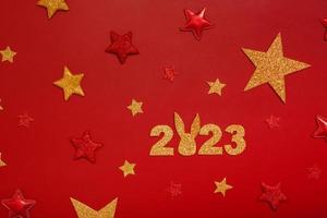 2023 Neujahrs-Flachkonzept mit Kaninchen. zahlen 2023 mit roten und goldenen sternen, draufsicht auf rotem hintergrund foto