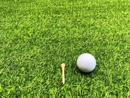 golfball nah oben auf grünem gras auf unscharfer schöner landschaft des golfhintergrundes.konzept internationaler sport, der auf präzisionsfähigkeiten zur gesundheitsentspannung angewiesen ist.