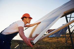 Handarbeit. männlicher Arbeiter in blauer Uniform im Freien mit Solarbatterien an sonnigen Tagen