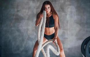 junge fitnessfrau mit schlankem körper und in schwarzer sportlicher kleidung ist im fitnessstudio foto