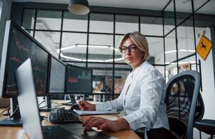 Börsenmaklerin in formeller Kleidung arbeitet im Büro mit Finanzmarkt foto