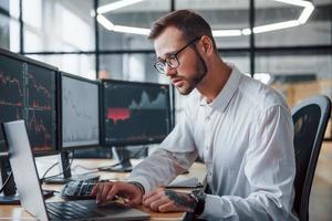 männlicher börsenmakler in formeller kleidung arbeitet im büro mit finanzmarkt foto