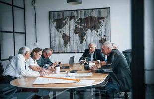 Ein älteres Team älterer Geschäftsmannarchitekten trifft sich im Büro und arbeitet mit einer jungen Frau zusammen foto