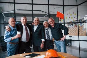 Ein älteres Team älterer Geschäftsmannarchitekten steht zusammen im Büro foto
