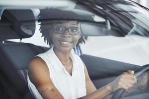 junge afroamerikanische frau sitzt im neuen modernen auto foto