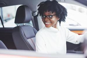 junge afroamerikanische frau sitzt im neuen modernen auto foto