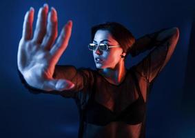 heiße brünette mit sonnenbrille posiert im studio mit neonbeleuchtung foto