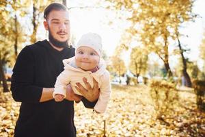 schönes Sonnenlicht. Vater in Freizeitkleidung mit seinem Kind ist im schönen Herbstpark foto