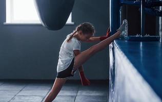 Dehnen vor Übungen. junges kleines mädchen in sportlicher kleidung ist im fitnessstudio und hat einen trainingstag. Konzeption des Boxens foto