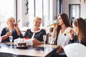 ältere frau mit familie und freunden, die drinnen einen geburtstag feiern foto