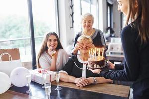 ältere frau mit familie und freunden, die drinnen einen geburtstag feiern foto