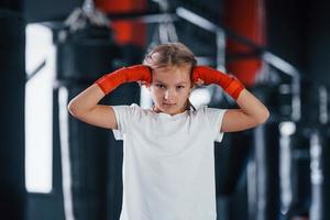 porträt eines jungen kleinen mädchens in sportlicher kleidung, das im fitnessstudio ist, hat einen trainingstag. Konzeption des Boxens foto