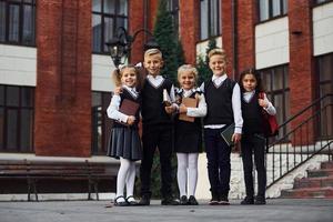 Gruppe von Kindern in Schuluniform, die sich im Freien in der Nähe des Bildungsgebäudes befinden foto