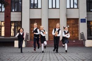 Gruppe von Kindern in Schuluniform, die zusammen im Freien läuft foto
