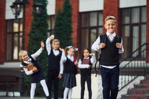 gruppe von kindern in schuluniform, die zusammen vor der kamera im freien in der nähe des bildungsgebäudes posieren foto