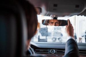 junger geschäftsmann im schwarzen anzug und krawatte, der modernes auto fährt foto