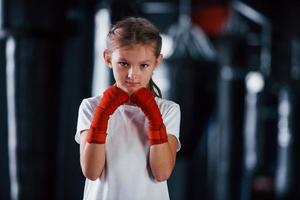 porträt eines jungen kleinen mädchens in sportlicher kleidung, das im fitnessstudio ist, hat einen trainingstag. Konzeption des Boxens foto