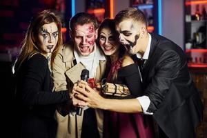 Freunde werden auf der Motto-Halloween-Party in schaurig geschminkten Kostümen Spaß haben und gemeinsam vor der Kamera posieren foto