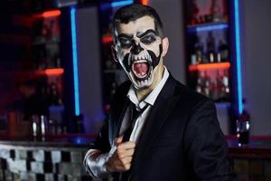 in die Kamera schreien. Porträt eines Mannes, der auf der thematischen Halloween-Party in gruseligem Skelett-Make-up und Kostüm ist foto