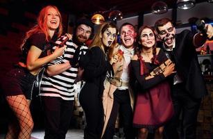 Freunde werden auf der Motto-Halloween-Party in schaurig geschminkten Kostümen Spaß haben und gemeinsam vor der Kamera posieren foto