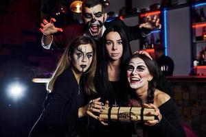 Bombe zeigen. Freunde ist auf der thematischen Halloween-Party in gruseligem Make-up und Kostümen foto