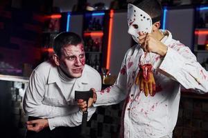 Freunde ist auf der thematischen Halloween-Party in gruseligem Make-up und Zombie-Kostümen foto