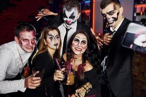 Freunde ist auf der thematischen Halloween-Party in gruseligem Make-up und Kostümen foto