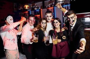 für die Kamera posieren. Freunde ist auf der thematischen Halloween-Party in gruseligem Make-up und Kostümen foto