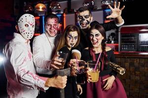 für die Kamera posieren. Freunde ist auf der thematischen Halloween-Party in gruseligem Make-up und Kostümen foto