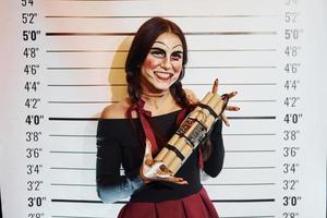 Porträt einer Frau, die auf der thematischen Halloween-Party in gruseligem Make-up und Kostüm mit Bombe in den Händen ist foto