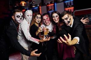 für die Kamera posieren. Freunde ist auf der thematischen Halloween-Party in gruseligem Make-up und Kostümen foto