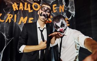 Freunde ist auf der thematischen Halloween-Party in gruseligem Make-up und Kostümen und schreit in die Kamera foto