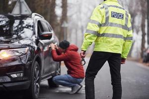 polizist in grüner uniform erwischt autodiebstahl auf der straße foto