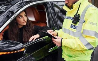 männlicher polizist in grüner uniform, der fahrzeug auf der straße überprüft foto