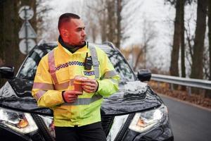 männlicher polizist in grüner uniform, der eine pause mit donut auf der straße macht foto