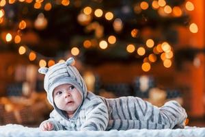 süßes kleines Baby, das sich im weihnachtlich dekorierten Raum hinlegt foto