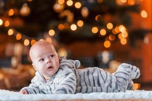 süßes kleines Baby, das sich im weihnachtlich dekorierten Raum hinlegt foto